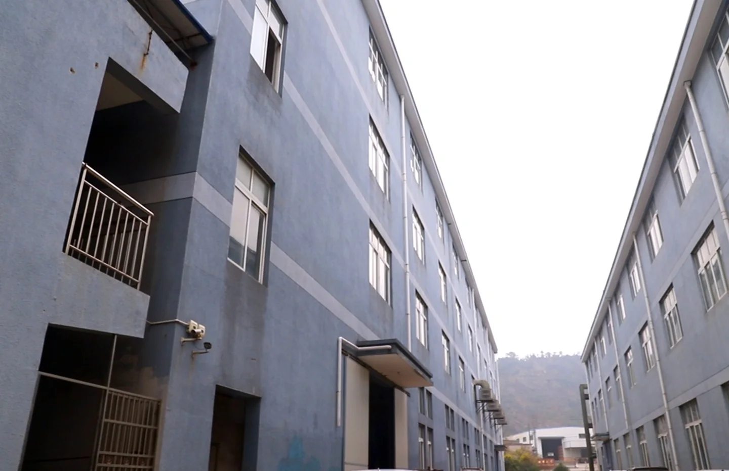 View between industrial buildings along a factory access road