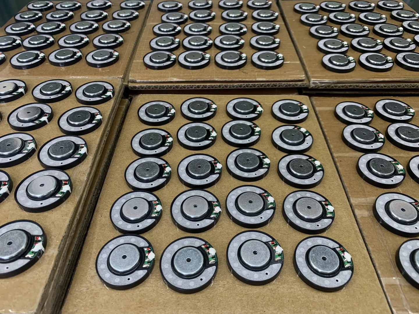 Small round audio driver units arranged in rows on cardboard