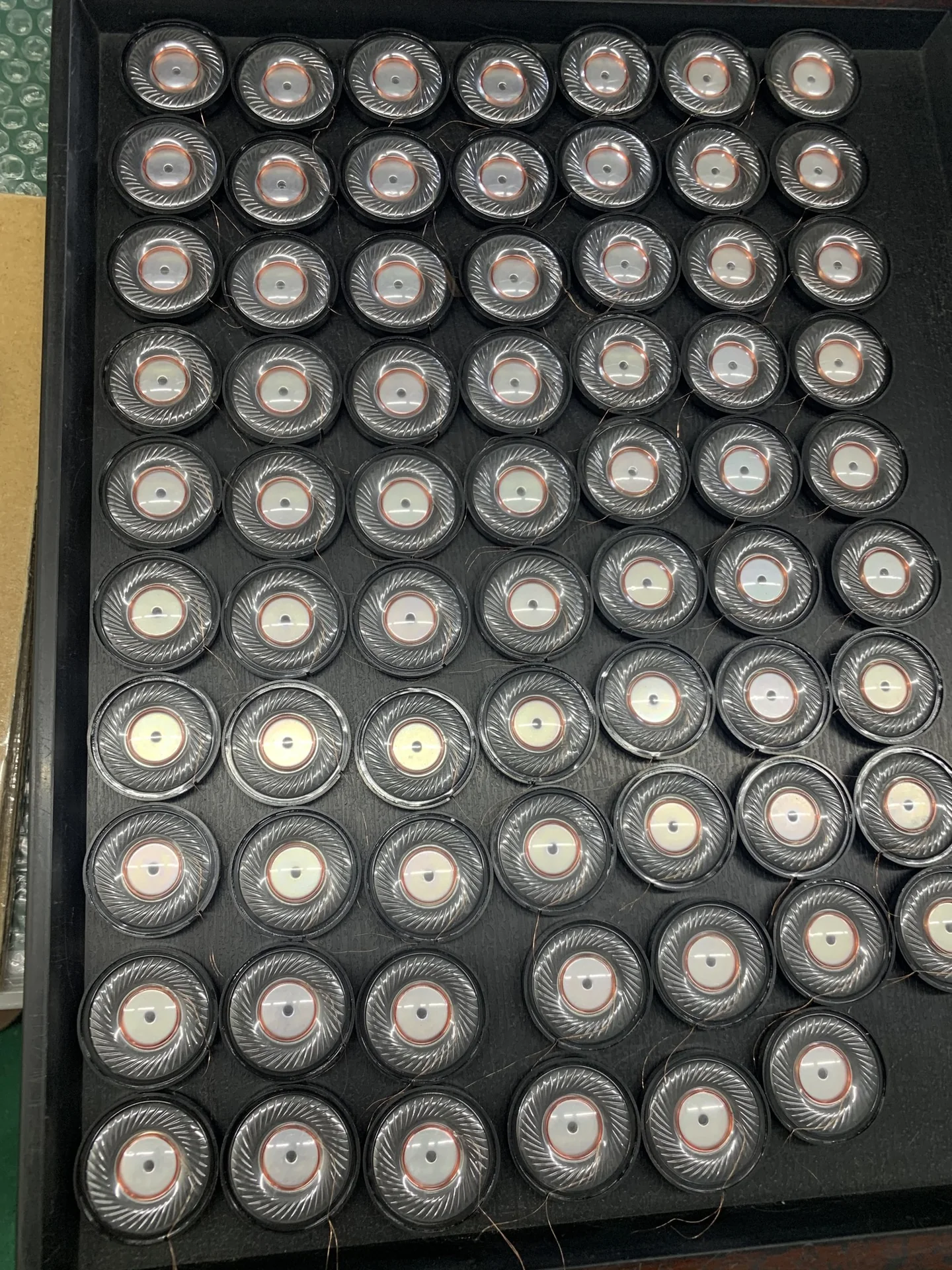 Rows of small round driver units arranged on a tray