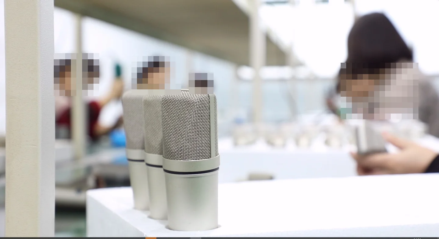 Microphone in the foreground with a production work area behind it